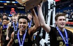 Apple Valley guard Tre Jones (3) and forward Mason Morse (24) marched their 4A championship trophy to the student section after defeating Champlin Par