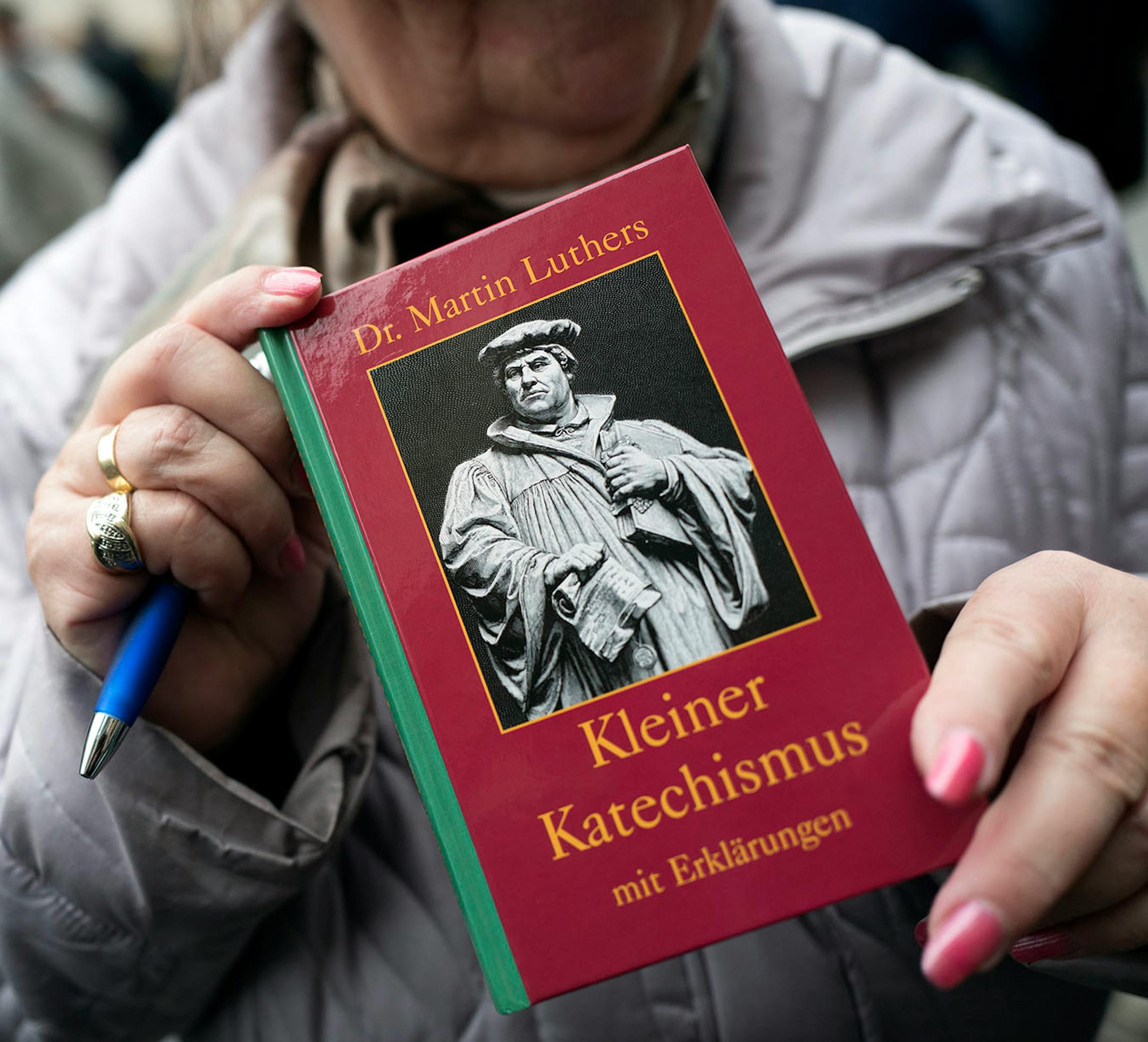 A woman held a book about reformer Martin Luther as she stood by Castle Church Monday October 31, 2016 in Wittenberg Germany. With church services, concerts and a city festival, the city is celebrating Reformation Day. Martin Luther is aid to have nailed his 95 Theses against the selling of indulgences onto the door of the Castle Church in Wittenberg on October 31, 1517.