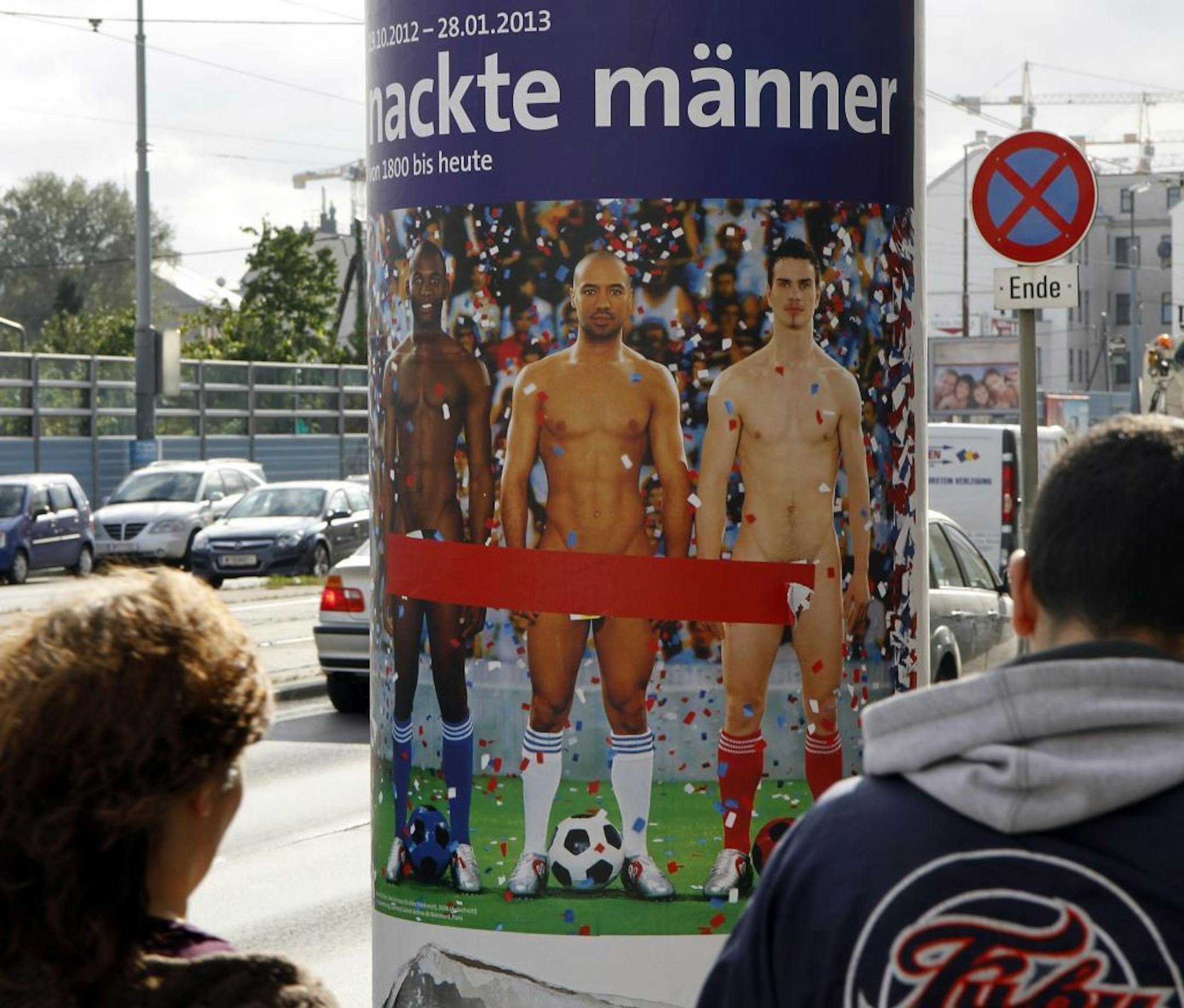 In this picture taken Oct. 18, 2012 two people walk past a poster showing three naked men which has had red tape added to cover the sensitive parts of the three men, in Vienna, Austria. Poster reads: "Naked Men". A prestigious Vienna museum, The Leopold Museum, has been forced to cover up a graphic poster advertising a new show devoted to male nudity, after protests that it is offensive. The show � "Nude Men from 1800 to Today" � opened its doors Friday Oct. 20, looking at how artists have dealt