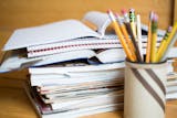 Stack of school books and pencil holder on desk.