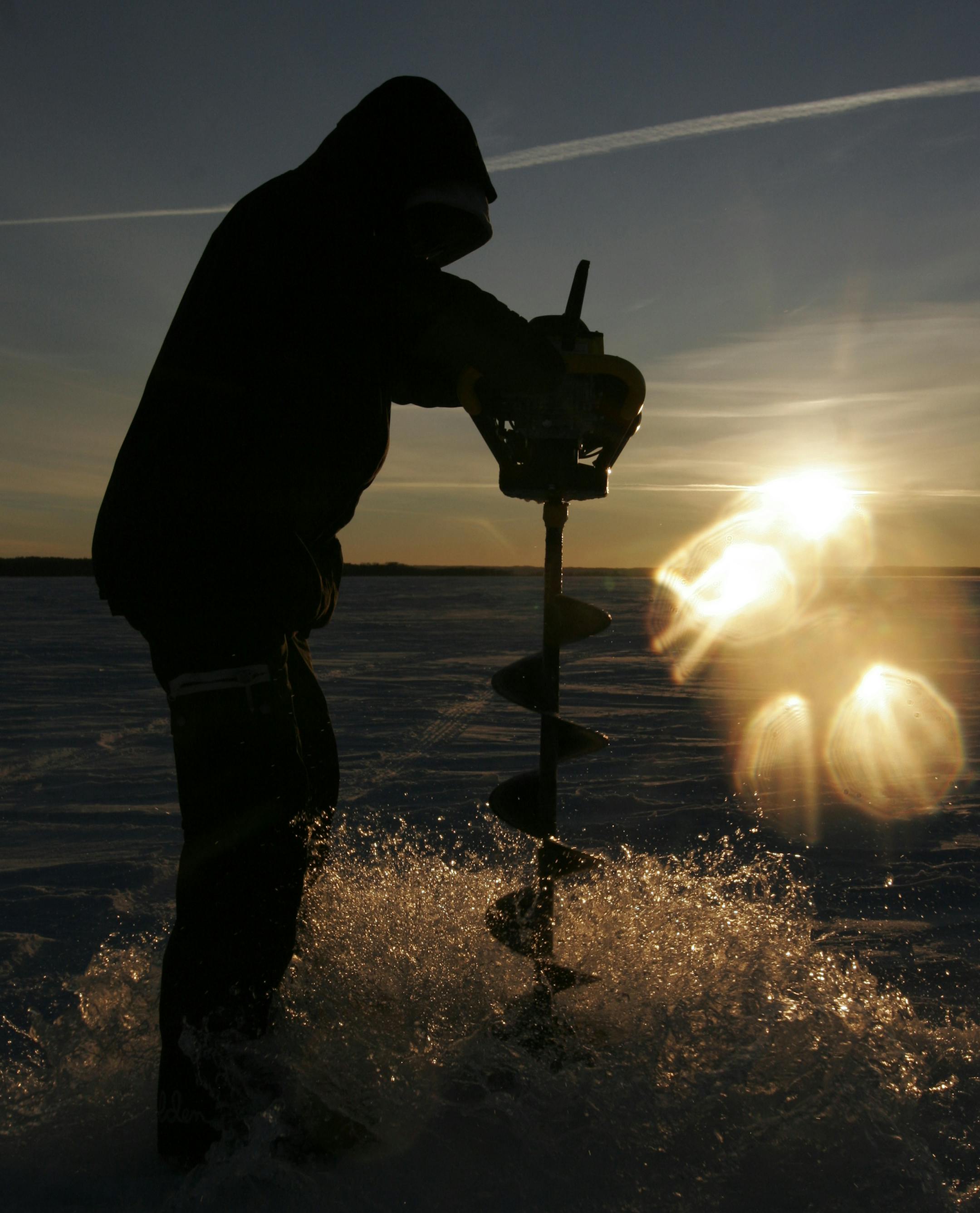 Doug Smith/Star Tribune; Jan. 23, 2014, Leech Lake, Mn. The setting sun reflects off the setting sun as Nate Rendulich pulled up an auger full of water after drilling an ice fishing hole on Leech Lake. ORG XMIT: MIN1402051133091597