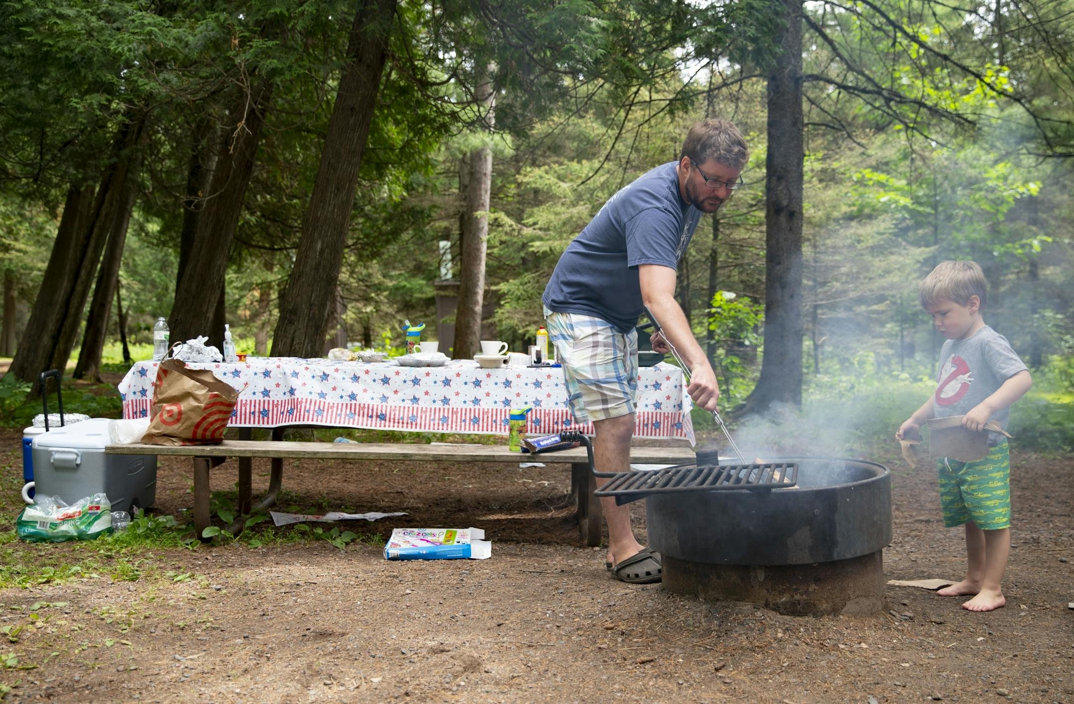 (Left) Tom McLafferty and his son, Tommy (5), tended to a fire they made in the grill at their campsite in Jay Cooke State Park on Wednesday.