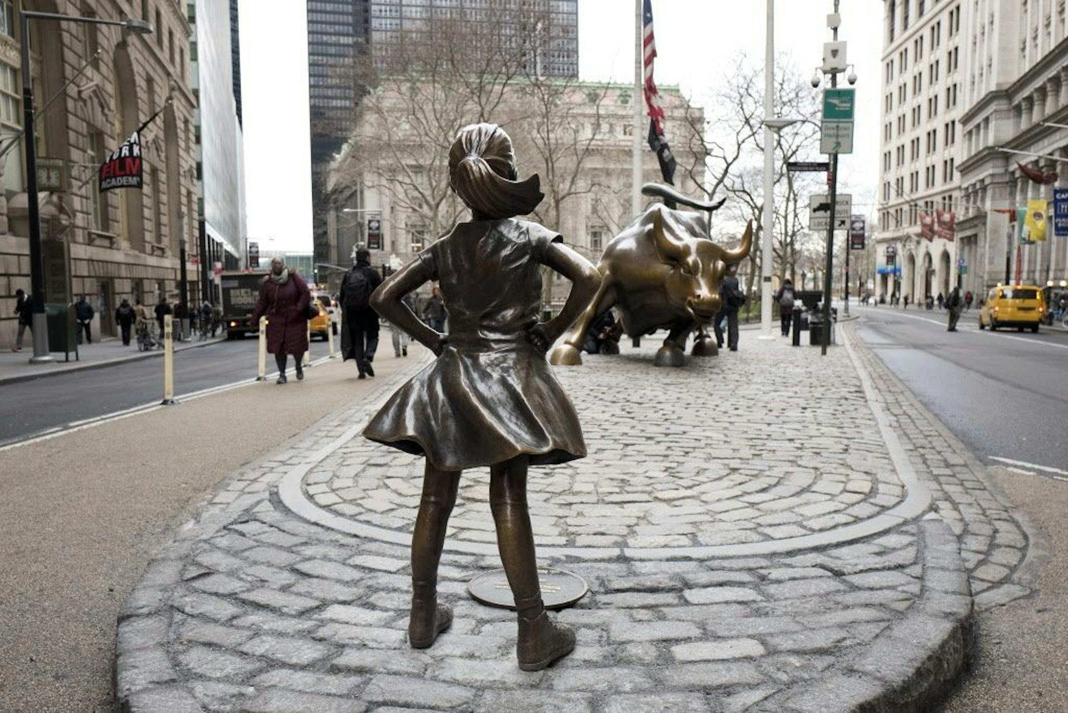The "Fearless Girl" statue faces Wall Street's charging bull statue, Wednesday, March 8, 2017, in New York. The statue was installed by investment firm State Street Global Advisors to highlight efforts to get more women on corporate boards. An inscription at the base reads, "Know the power of women in leadership. She makes a difference."