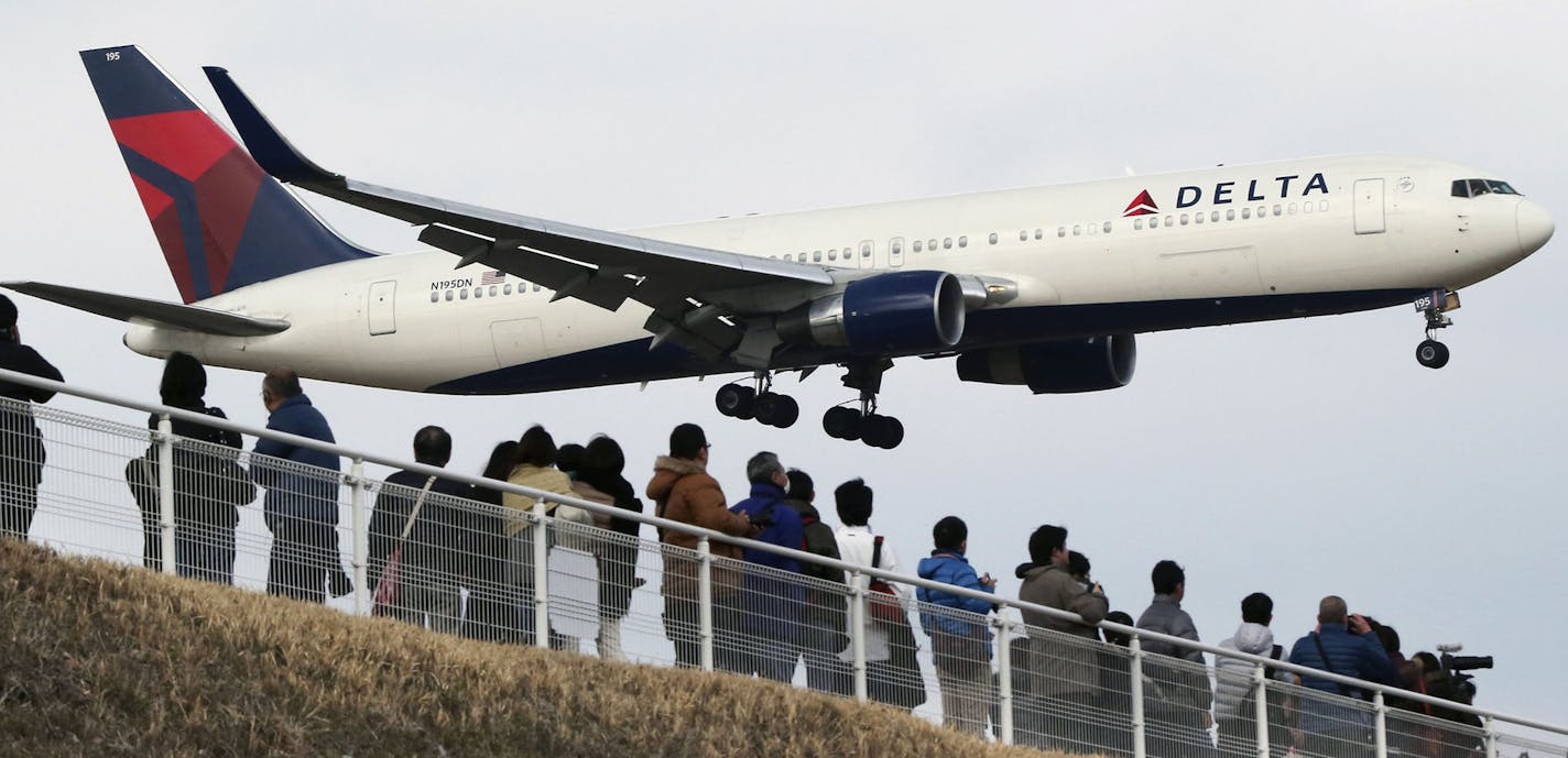 FILE - In this March 14, 2015 file photo, people watch a landing Delta Air Lines jet approach the Narita International Airport from a popular viewing spot at Sakuranoyama Park in Narita, east of Tokyo. Delta Air Lines reports quarterly financial results on Wednesday, April 15, 2015. (AP Photo/Koji Sasahara, File) ORG XMIT: MIN2015052711152217 ORG XMIT: MIN1602011111023316