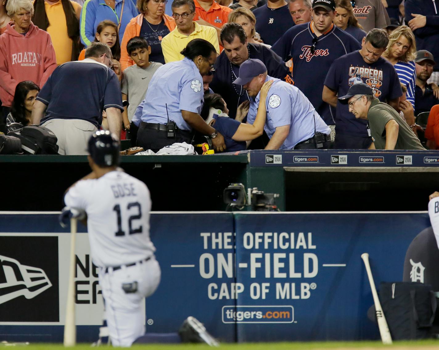 A fan is helped into a stretcher after being hit with a foul ball off the bat of Detroit Tigers' Anthony Gose, foreground, during the eighth inning of a baseball game against the Texas Rangers at Comerica Park Friday, Aug. 21, 2015, in Detroit.