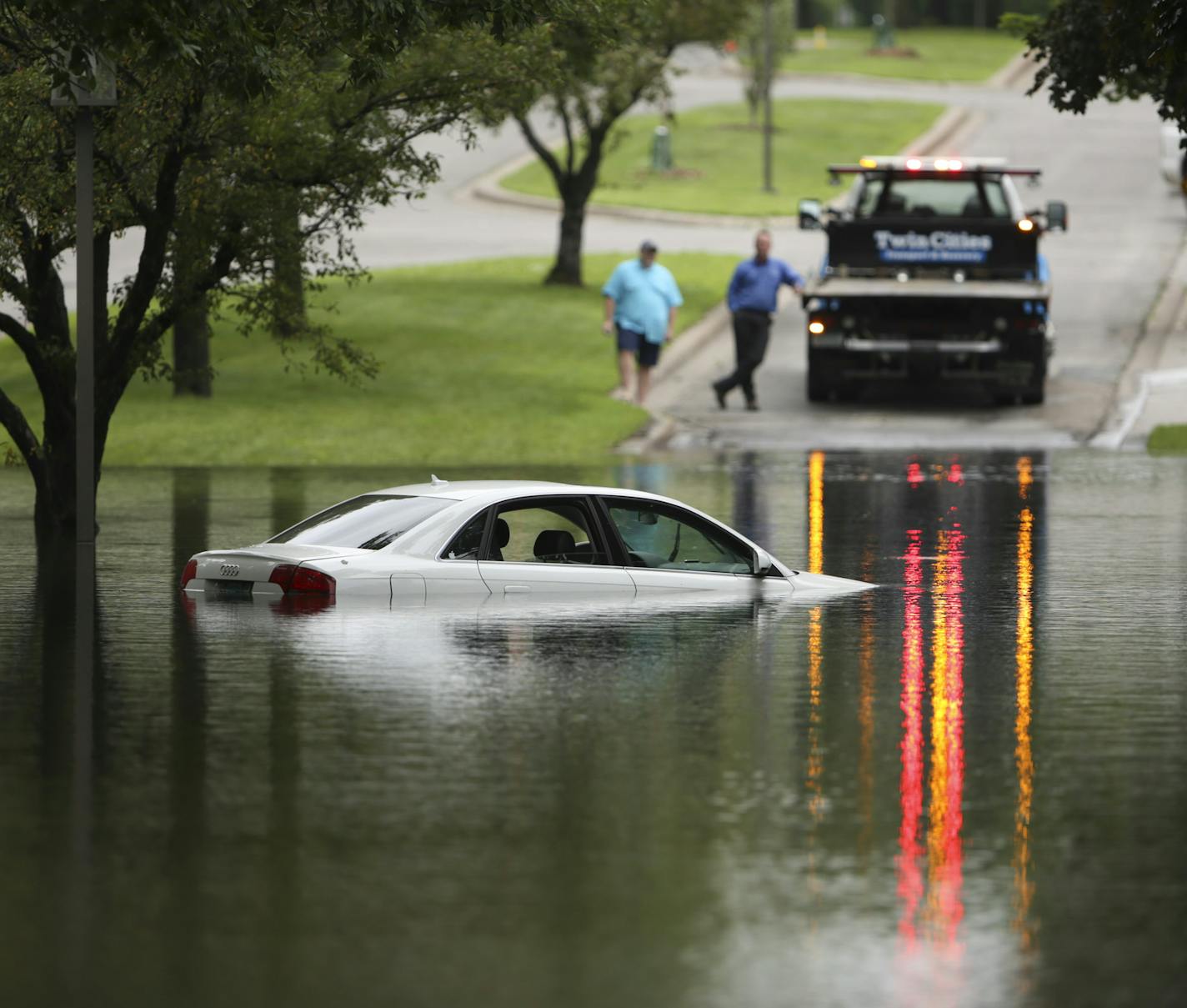 A tow truck waited to remove a car that was partially submerged on Kings Highway next to Lakewood Cemetery in Minneapolis Thursday afternoon.