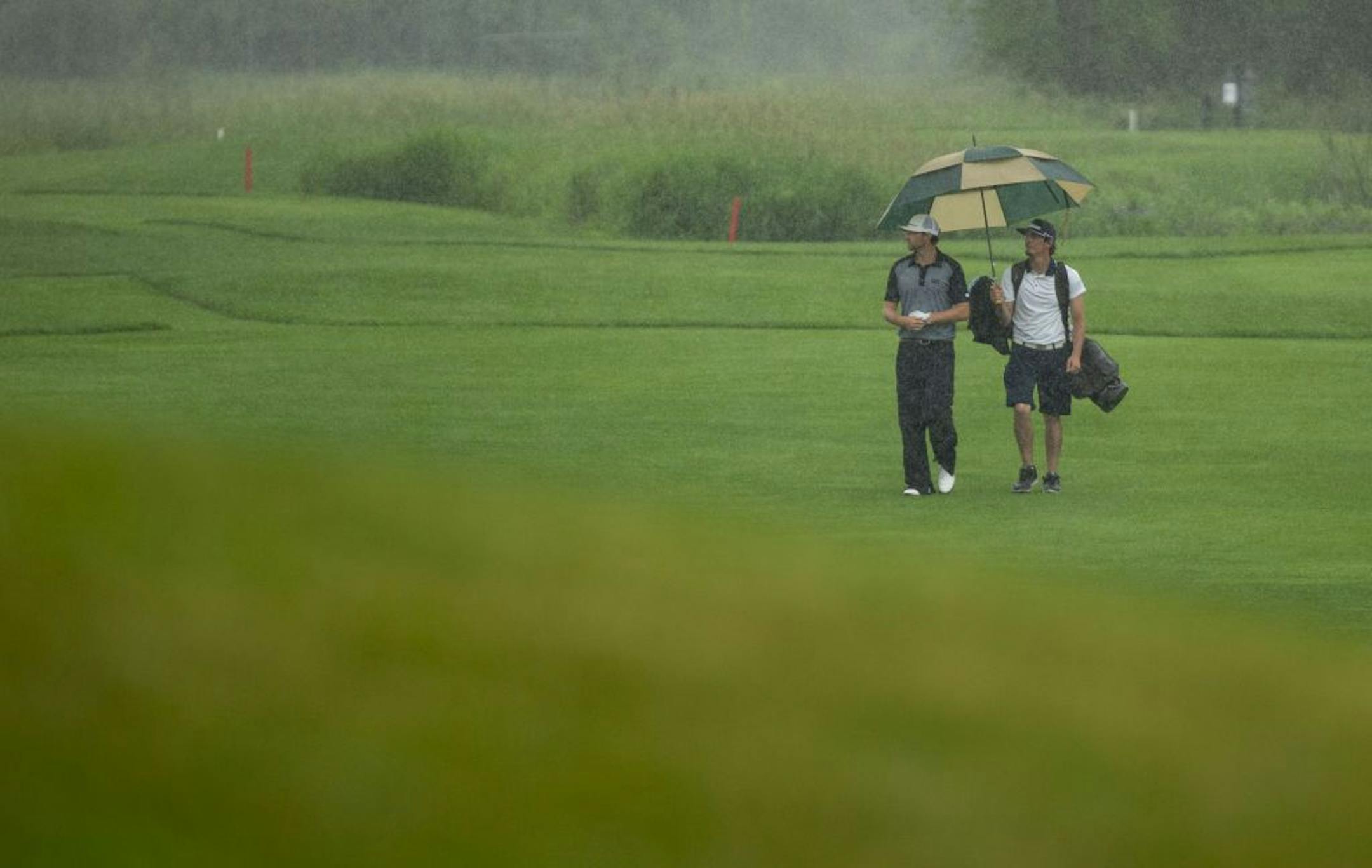 Robert Bell (left) and his caddy, Scott Janson, walk towards the eighteenth green during a rain storm on Monday. ALEX KORMANN ¥ alex.kormann@startribune.com A Monday qualifying round round of golf was held at Victory Links course on Monday July 1, 2019 to determine who would make the cut for the 3M open to be held this week. Many hopefuls played their hearts out in an effort to earn one of four spots up for grabs in the PGA Tour event.