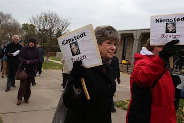 Diane Plocher, of Mayer, braved the cold and wind along with other protesters to march for the resignation of Archbishop John Nienstedt across the str