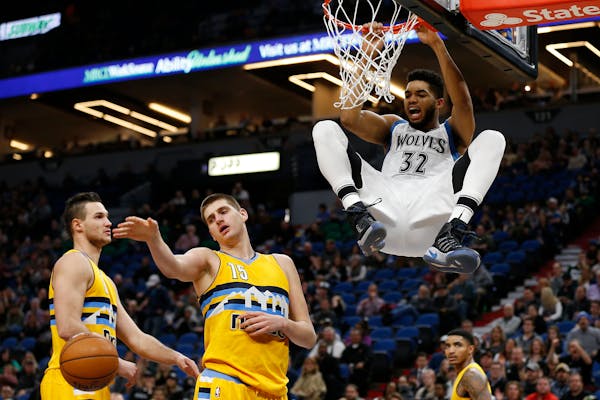 Timberwolves center Karl-Anthony Towns hung from the hoop after dunking against the Nuggets in the first half Sunday.
