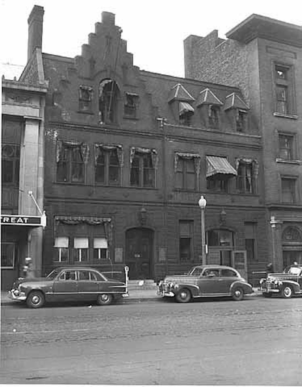 The three-story Northwestern Miller Building, shown in 1953, was a rare commercial example of the Tudor Revival style, featuring a rusticated stone base with brick above. Its most eye-popping feature was a tall step gable, the only one of its kind in downtown Minneapolis.