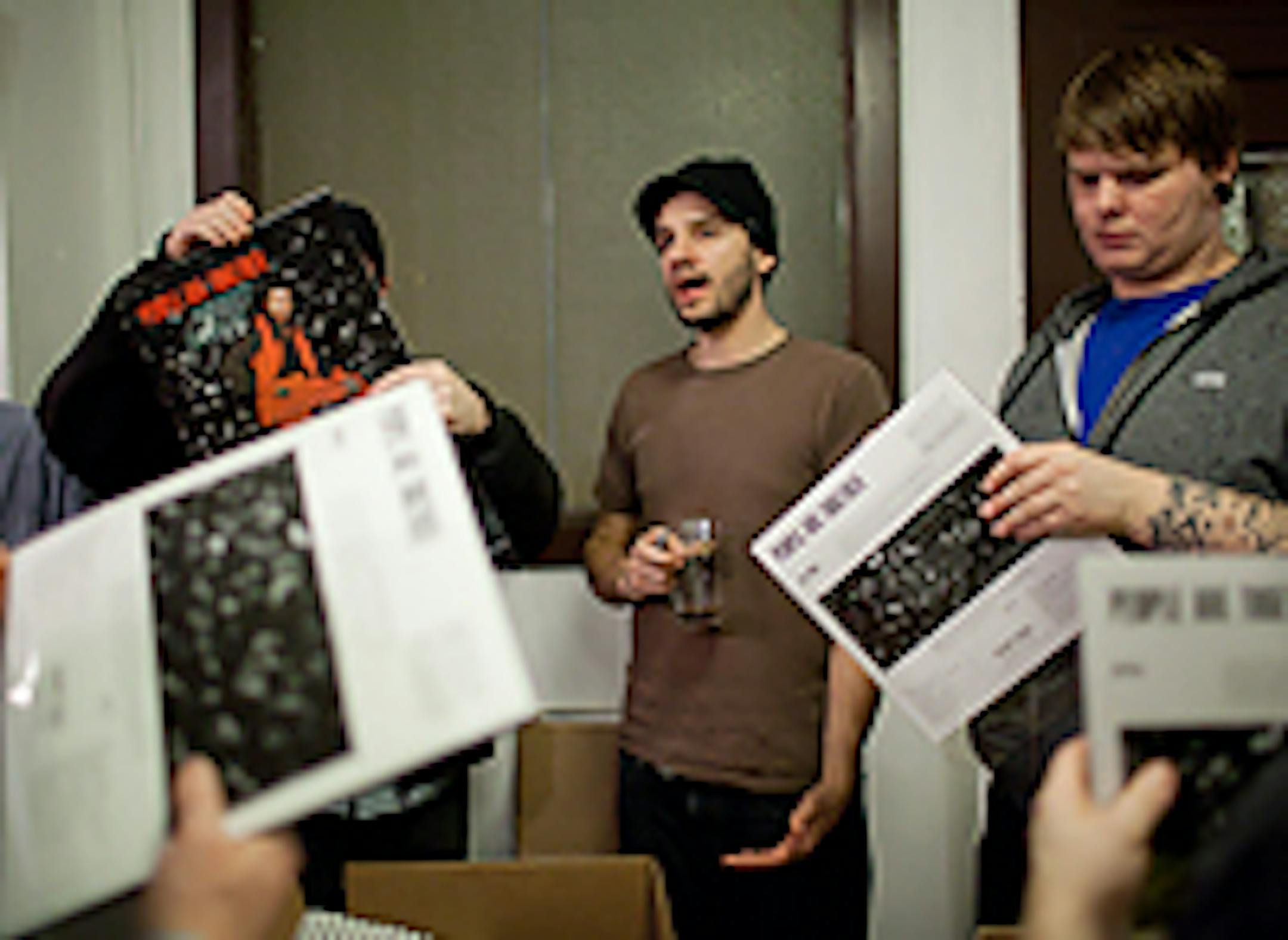Secret Stash Records co-founder Eric Foss, center, talked records with packing volunteers Dan McAllister, left, and Jonah Frailing, right, during the label's "packing party"