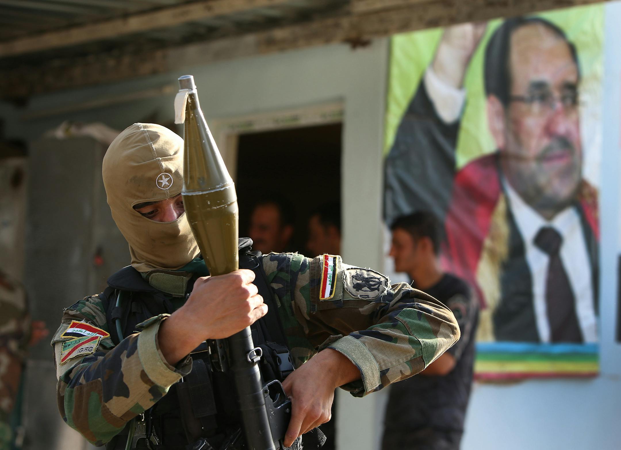 An Iraqi Shiite Turkmen gunman holds his RPG as he stands in front of a portrait of Iraqi Prime Minister Nouri al-Maliki, right, at the front line village of Taza Khormato, in the northern oil rich province of Kirkuk, Iraq, Friday June 20, 2014. Thousands of people fled the town of Taza Khormato fearing the advance of Sunni insurgents who overran the neighboring village of Kirkuk. Taza Khormato residents said insurgents led by the al-Qaida inspired Islamic State in Iraq and the Levant seized the