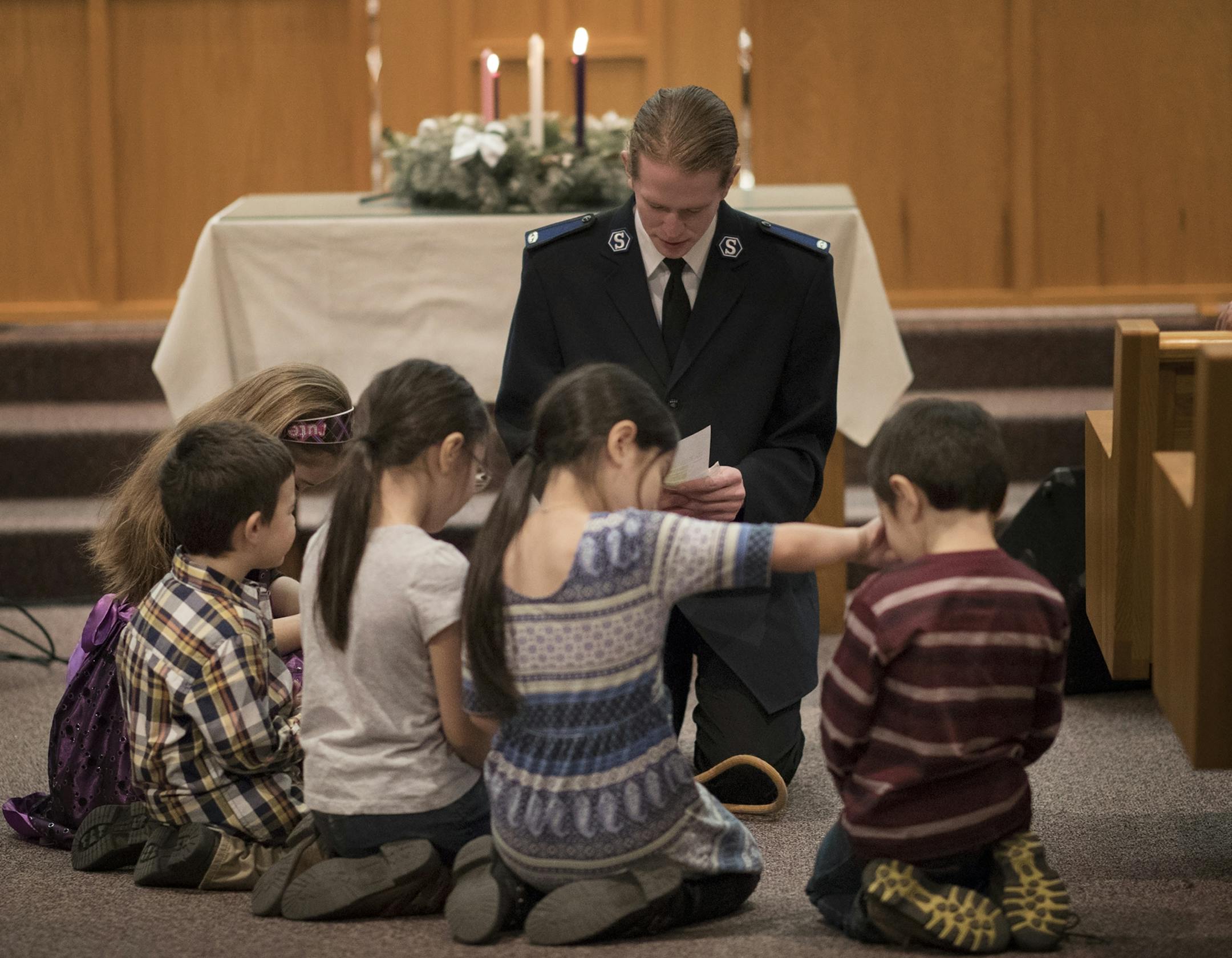 Richard Thalman lead a prayer with children during worship services at the Salvation Army Center Sunday December 10, 2017 in Maplewood MN.
