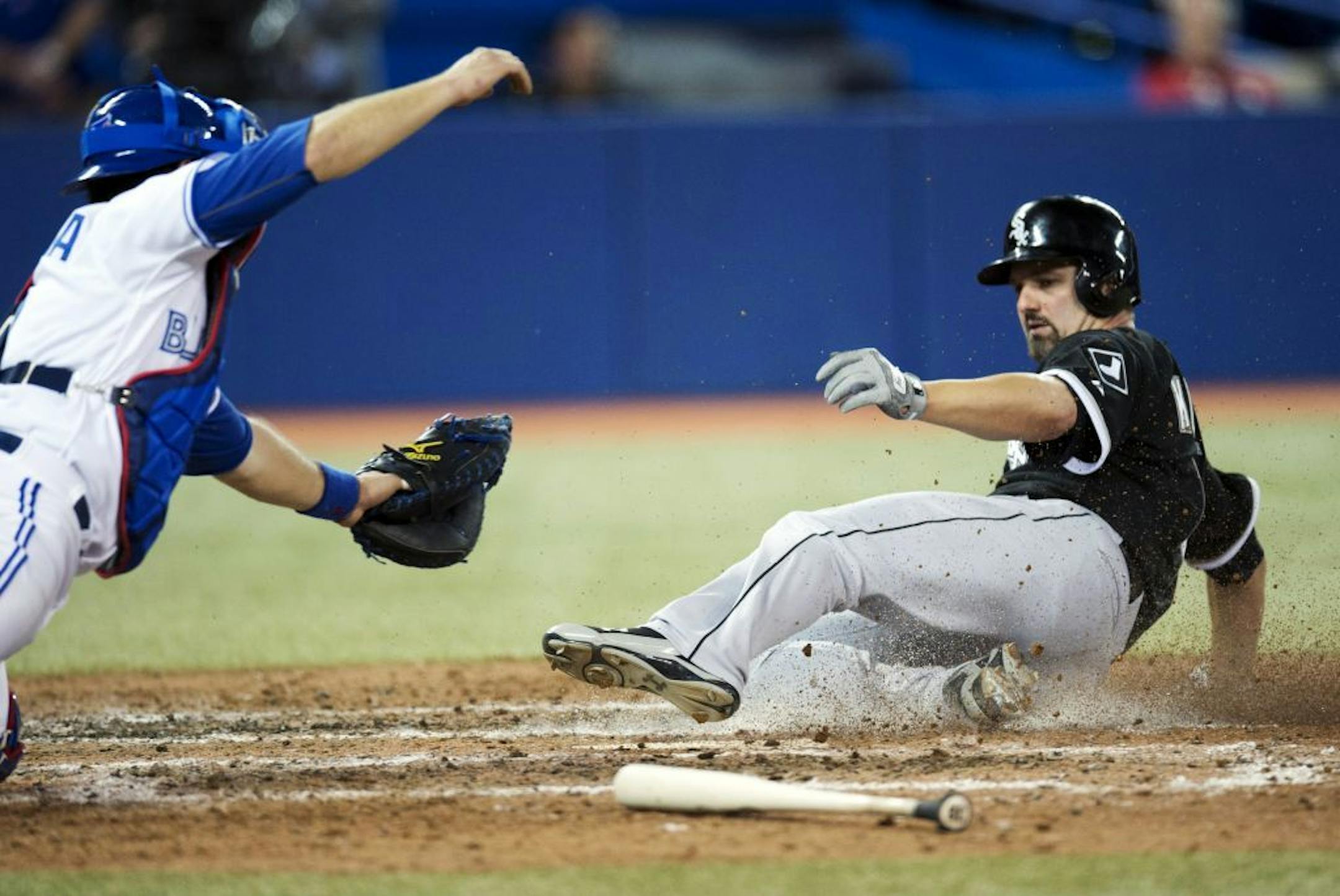 Toronto Blue Jays catcher J.P. Arencibia dives to try to make the tag as Chicago's Paul Konerko slides into home plate for the game-winning run.