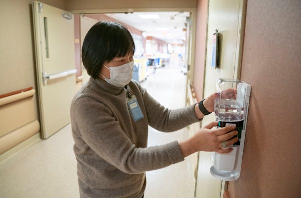 Dr. Hsieng Su, Allina Health’s senior vice president and chief medical executive, replaces hand sanitizer bottles as part of the Helping Hands volun