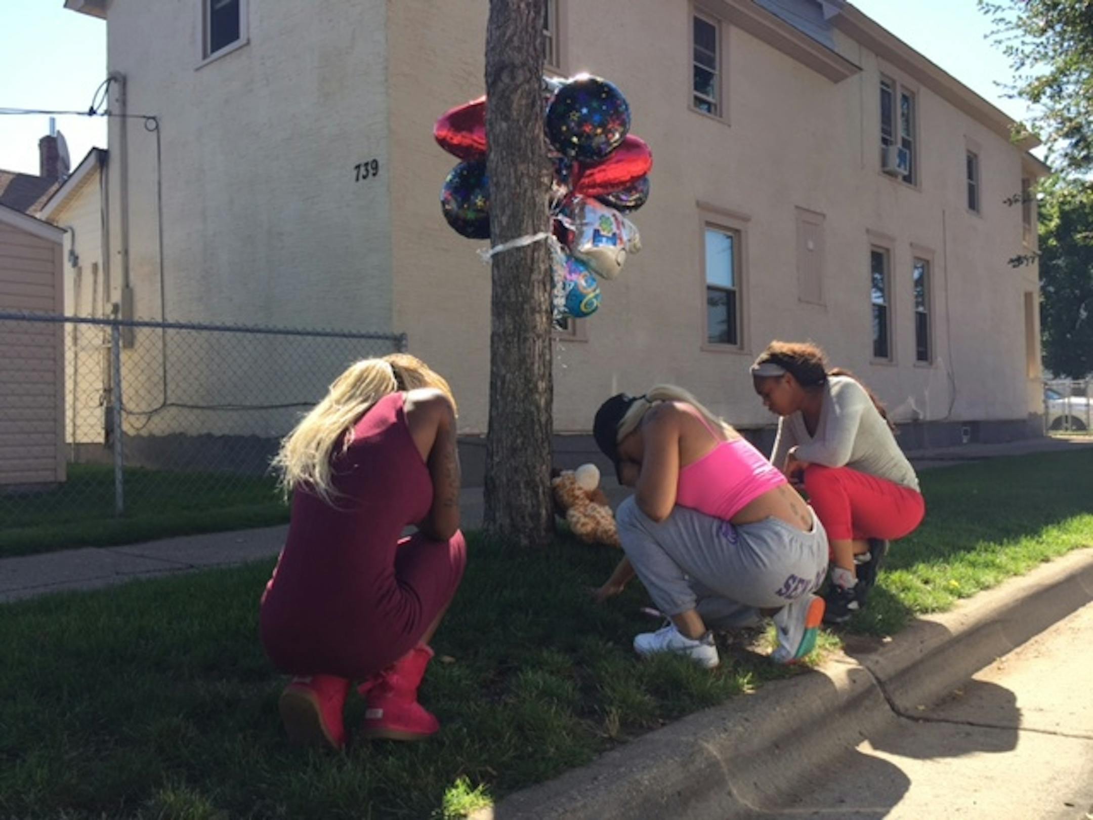 Kin Reynolds' cousin, Zenobia Barber, friend Trenika McGee and cousin Kalosha Minor gather at a memorial on Grotto Street just north of Edmund Avenue in St. Paul to remember Reynolds, who was shot and killed Tuesday evening.