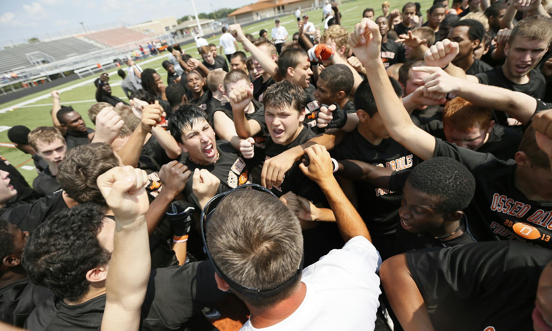 Members of the Osseo football team surrounded Orioles coach Derrin Lamker on Monday. "Playing with an edge means you go to the whistle and play nasty," Lamker said.