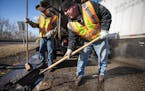 Street service workers Bradley Therres, left, and Lance Hamby filled potholes on Shepard Road in St. Paul in March.