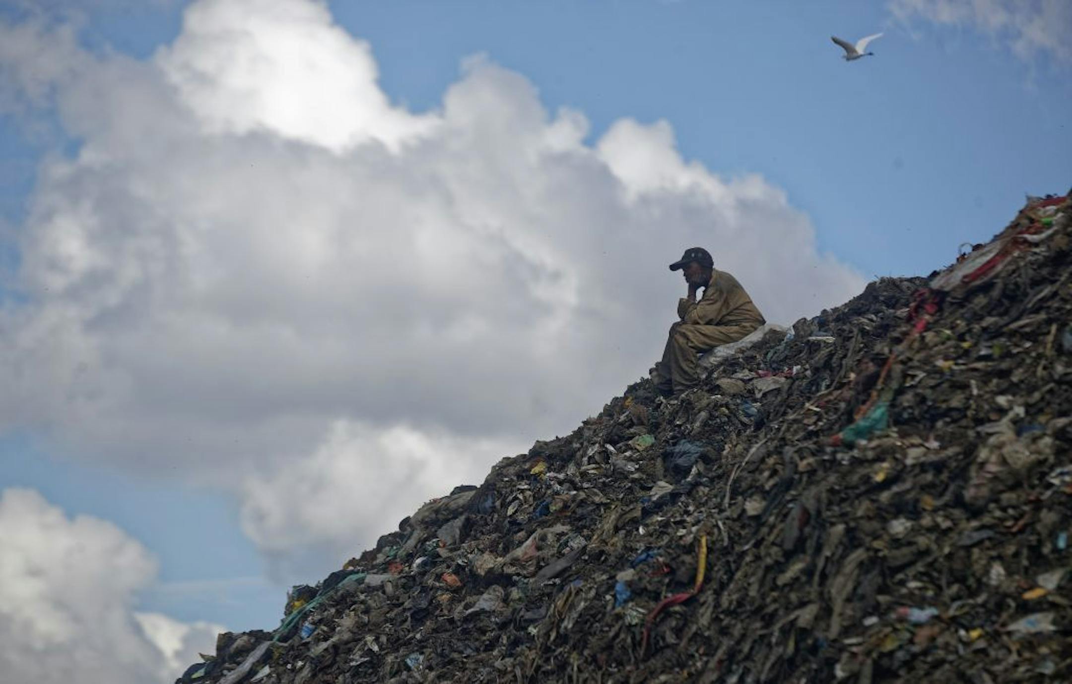 In this photo taken Wednesday, Dec. 5, 2018, a man who scavenges for recyclable materials for a living takes a break on top of a hill of garbage at the dump in the Dandora slum of Nairobi, Kenya. As the world meets again to tackle the growing threat of climate change, how the continent tackles the growing solid waste produced by its more than 1.2 billion residents, many of them eager consumers in growing economies, is a major question in the fight against climate change.