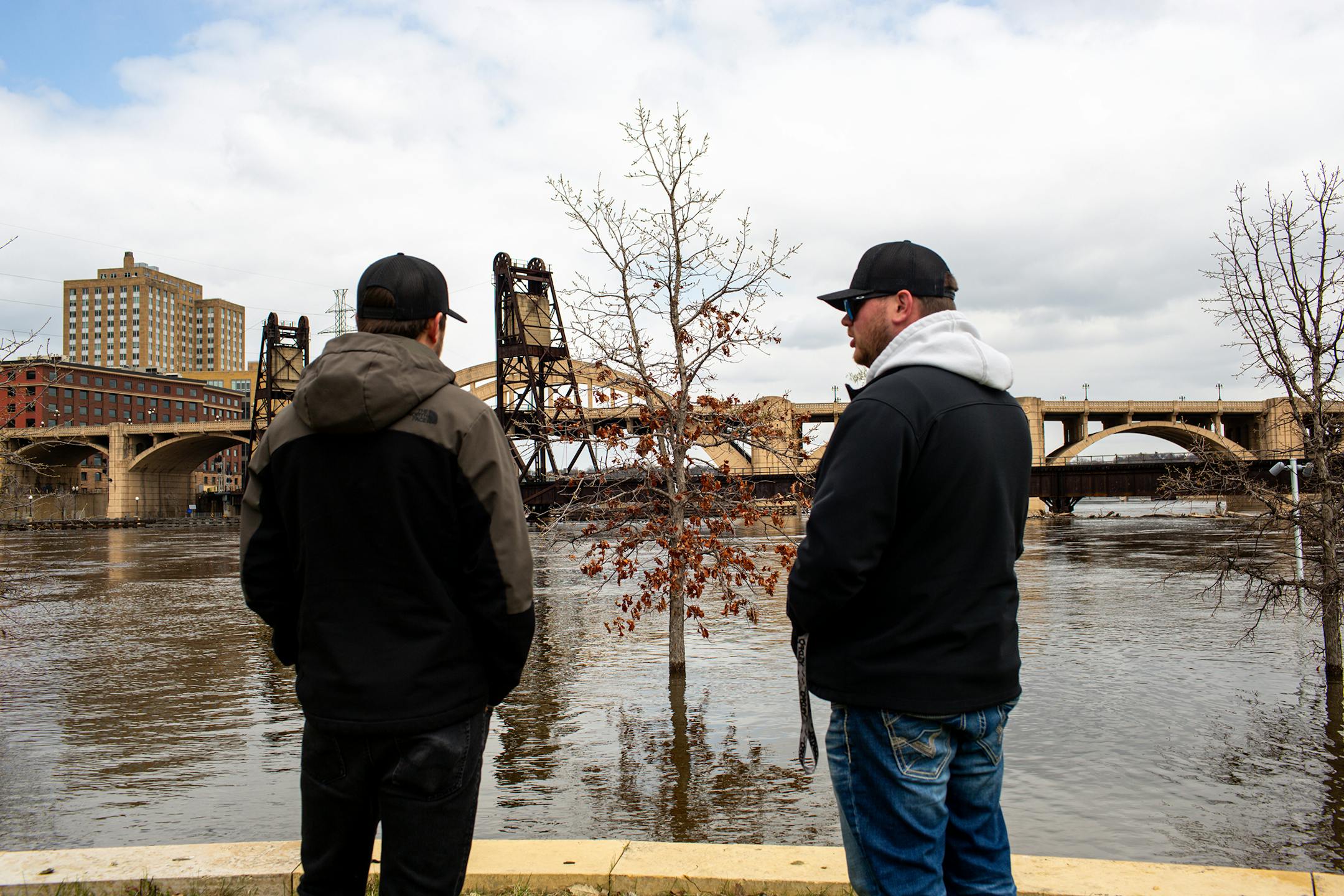 Austin Carlson of Prior Lake, left, and Matt Theis of Shakopee, right, look out over the partially submerged park on Raspberry Island Sunday, April 23, 2023, during a period of high spring flooding in St. Paul.