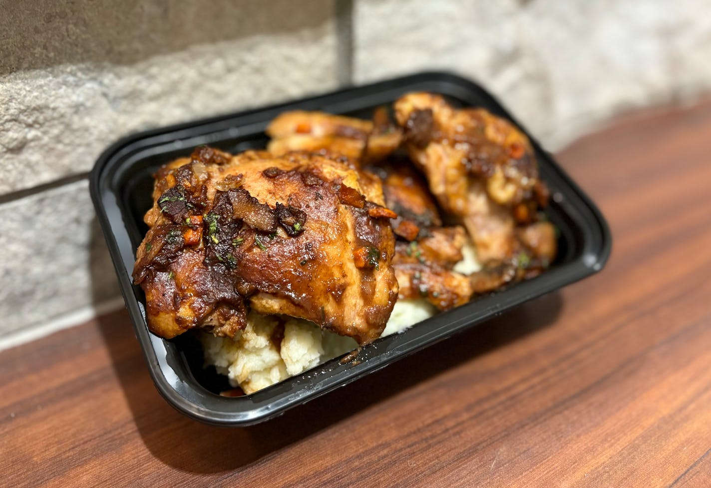 A take away tray filled with chicken with a light amount of mushroom gravy over mashed potatoes