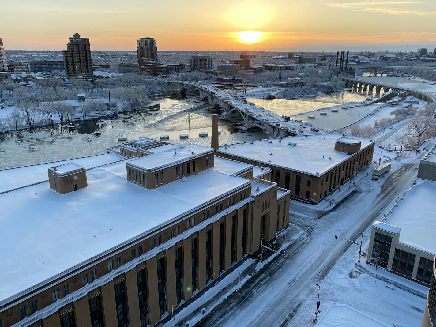 View of downtown Minneapolis and the Stone Arch Bridge with sun rising.