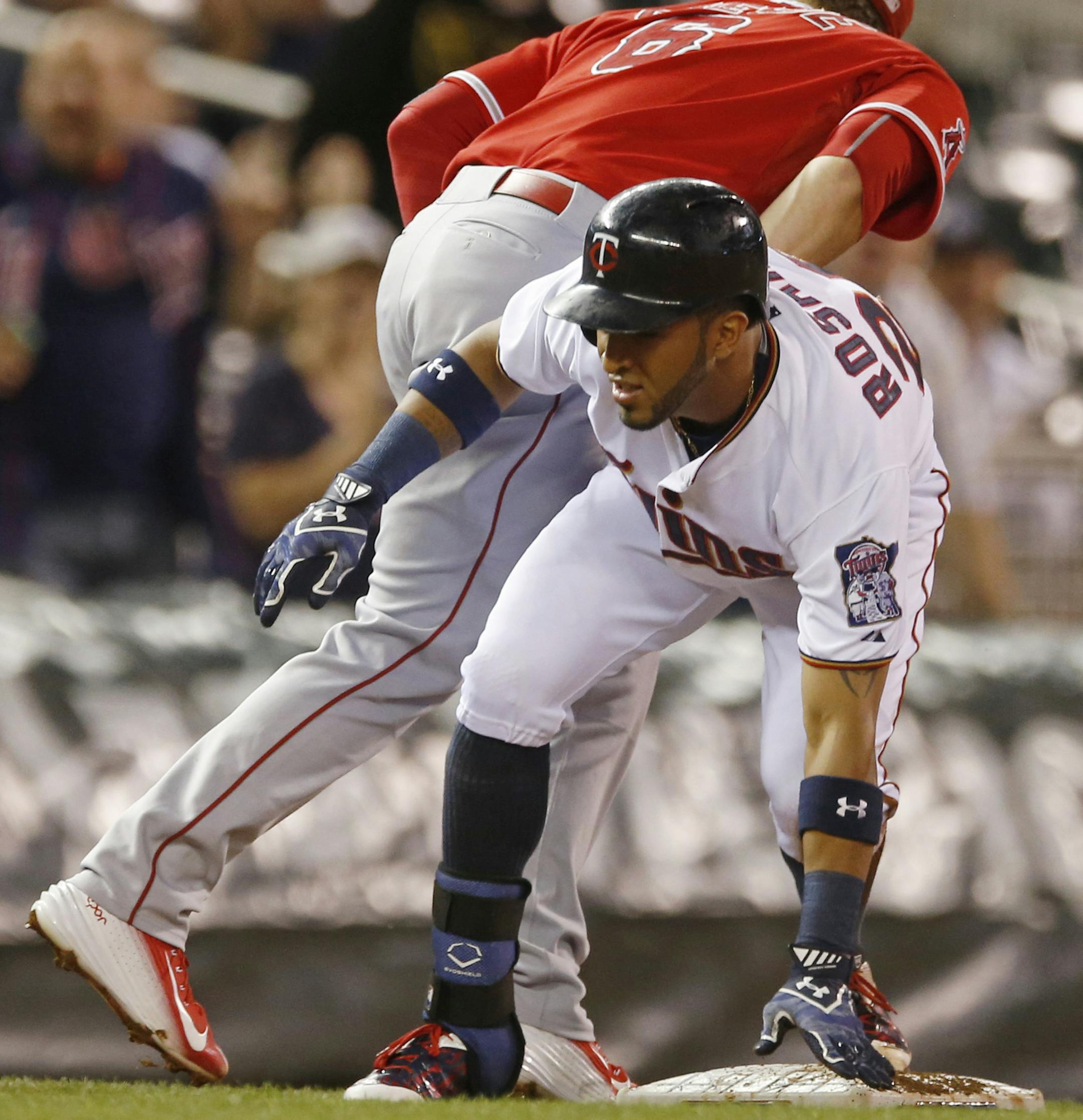 Minnesota Twins&#x2019; Eddie Rosario, right, stands on third with a triple off Los Angeles Angels pitcher Hector Santiago during the first inning of a baseball game, Thursday, Sept. 17, 2015, in Minneapolis, beating a tag by Angels third baseman David Freese. (AP Photo/Jim Mone)