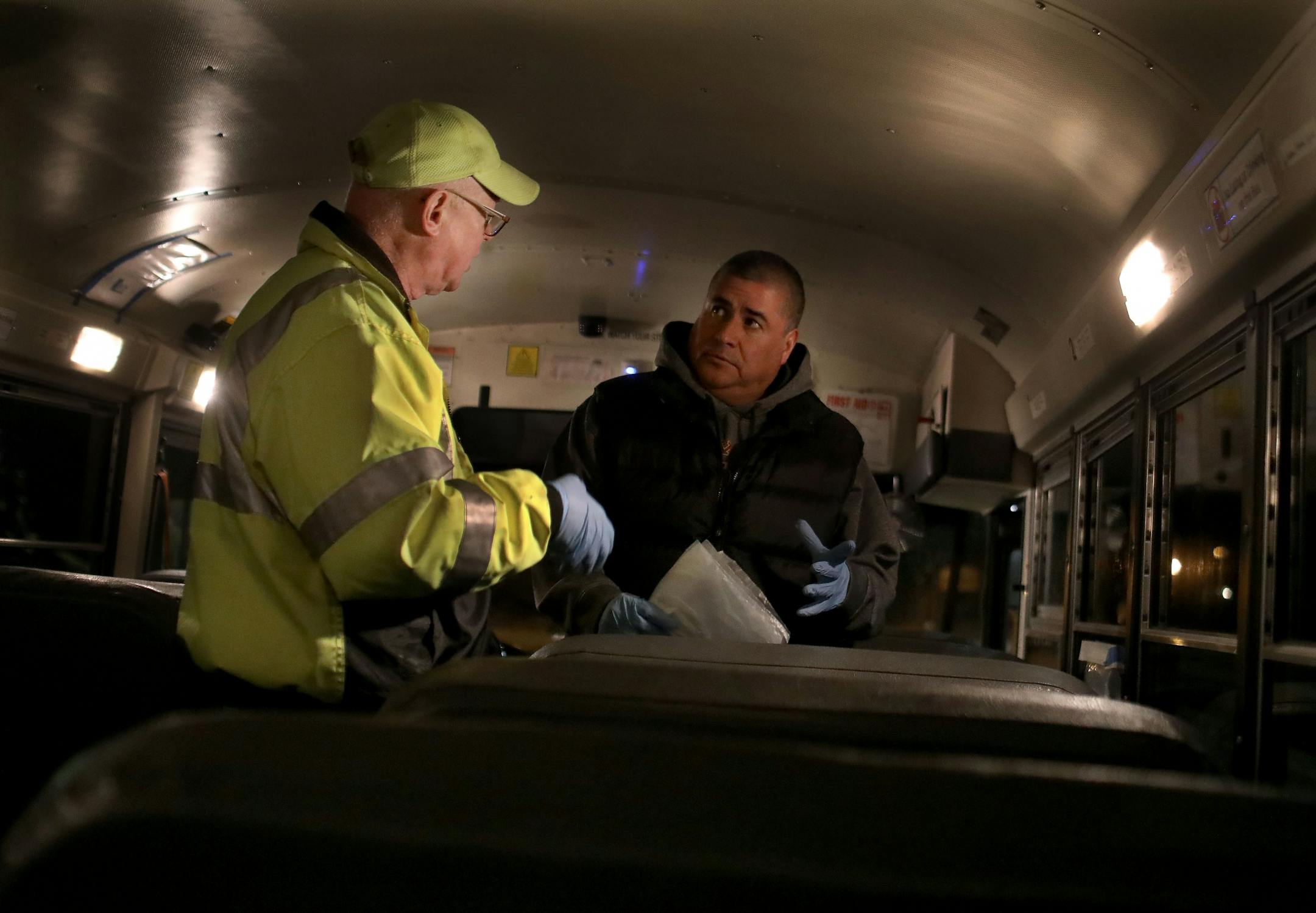 St. Paul school bus drivers and aides headed out a week's worth of breakfasts and lunches to families of students along their route Wednesday, March 25, 2020, in St. Paul, MN. Here, Charles Rice, left, bus driver and retired surgery nurse, and Dave Vibar, St. Paul School district employee who was helping with deliveries, talked in the bus before heading out on the route to deliver meals.