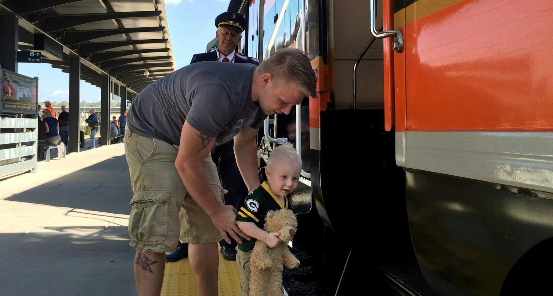 Retired Great Northern Railroad conductor Gary Nelson looks on as Colten Just, 2, is helped down from his first look inside a train by his father, Jason Just, of Hudson. They were at the renovated Union Depot for a railway history celebration replete with tours through the depot, a movie, talks, and a chance to see a vintage locomotive, coach car and caboose on display. ¬†