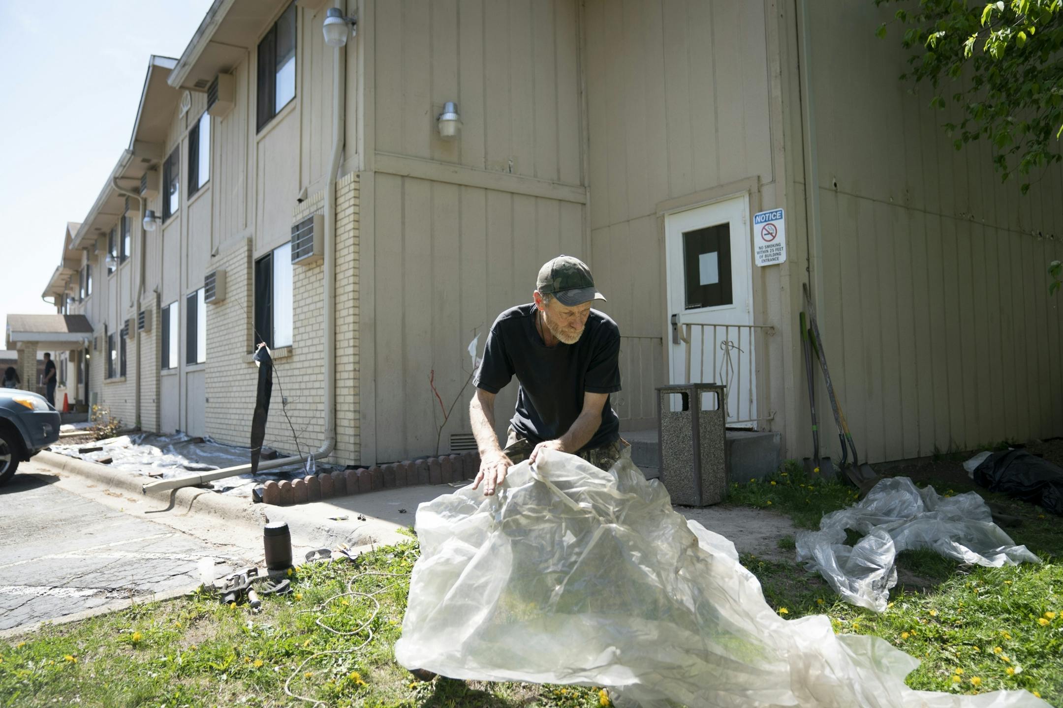 Paul Lipinski laid out plastic he had collected from the former campsite where he lived homeless for 20 years and used it to cover landscaping for a weed barrier as he picked up some landscaping work at the Super 8 in Chaska, Minn., on Friday, May 15, 2020. Lipinski was homeless for 20 years, according to him living in a camp in the woods nearby. This December he moved into the Super 8 for traditional housing and in February moved into his own apartment.