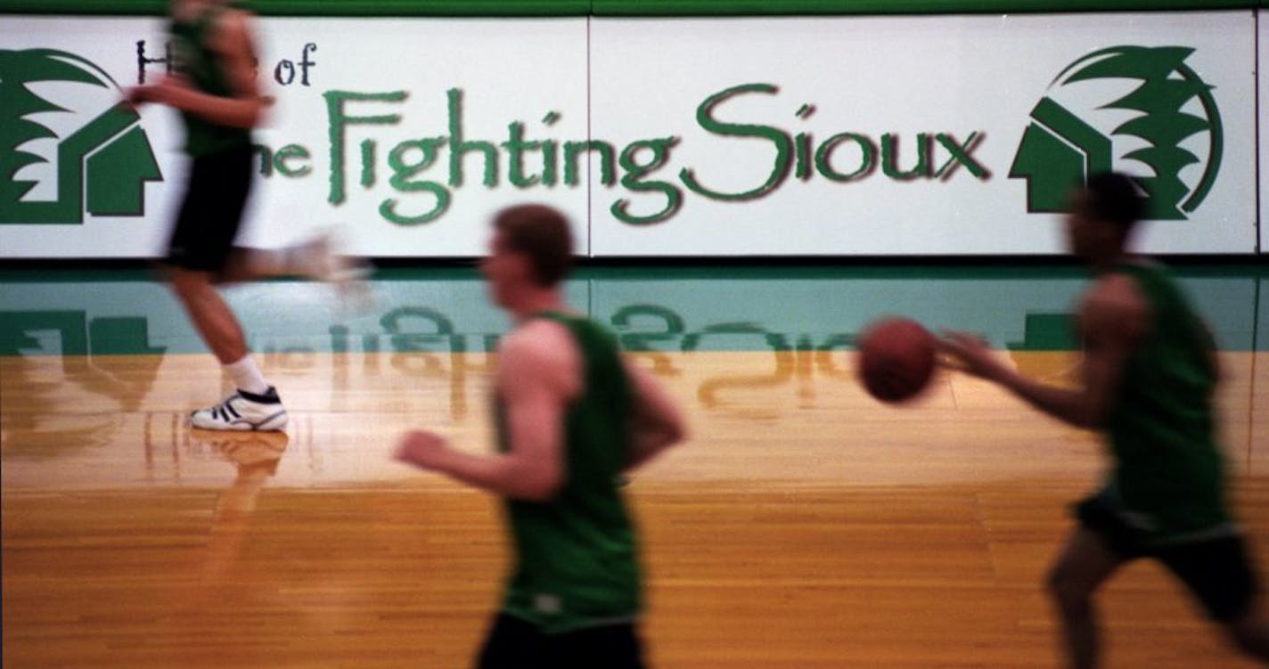 Members of the UND men's basketball team run pass the team's nickname and logo during a Tuesday afternoon practice.