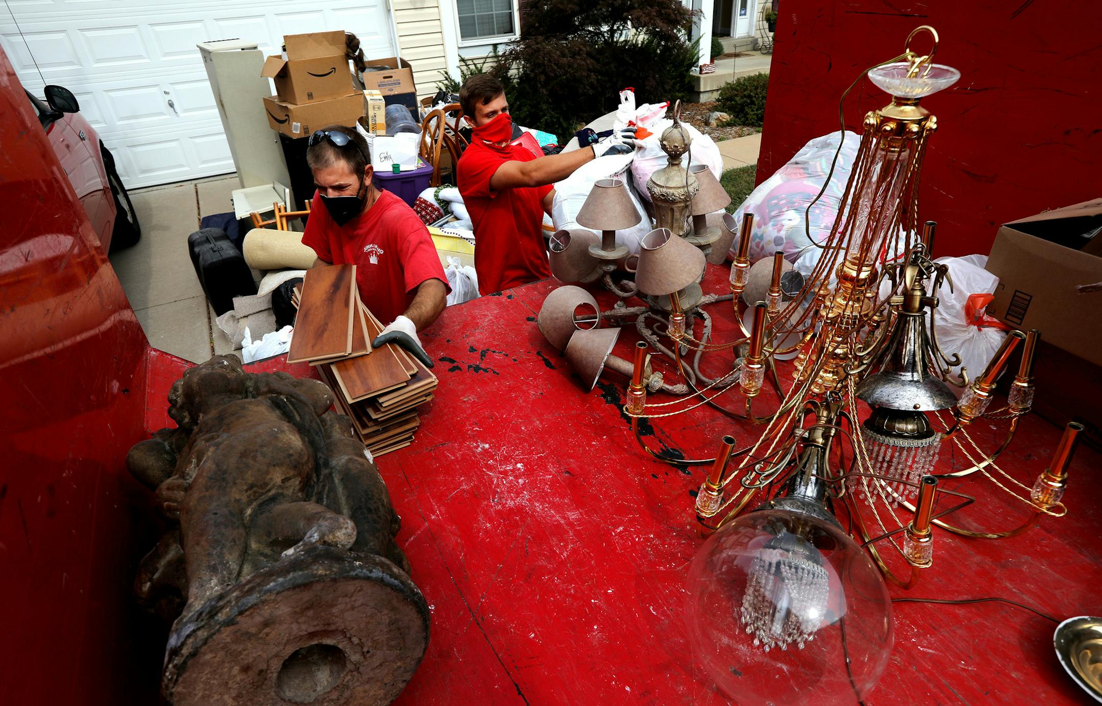 Movers Evan Pennycook left, and Brandon Smith, right, with Junk King, load boxes and bags full of unwanted items from a home onto their truck Tuesday, Sept. 22, 2020, in Lake St. Louis, Missouri. The homeowner said he has been working in his basement during the coronavirus pandemic and got tired of looking at all the junk that accumulated in his basement over the last 15 years. (Laurie Skrivan/St. Louis Post-Dispatch/TNS) ORG XMIT: 1788091
