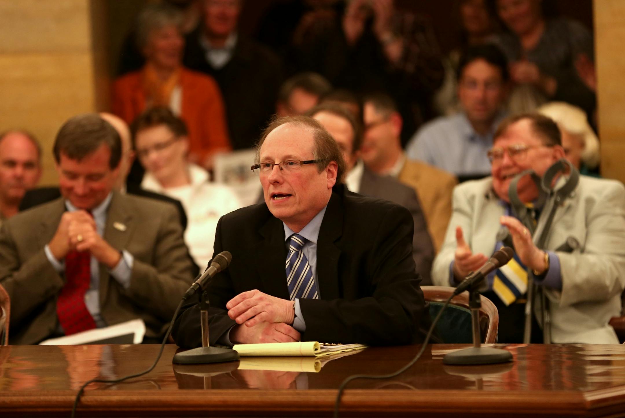 Some of the crowd behind him applauded as David Feinwachs compared the potential Fairview-Sanford merger to the public library being taken over by Wal-Mart as he testified during a hearing with Minnesota Attorney General Lori Swanson on the proposed takeover.