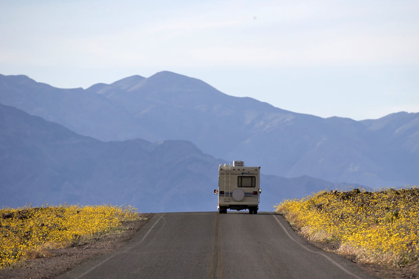 FILE - In this Feb. 24, 2016, file photo, wildflowers bloom as an RV travels along the road near Badwater Basin in Death Valley, Calif. Heading out on a road trip in a recreational vehicle allows travelers a unique opportunity to explore the nation while enjoying some comforts, too. (AP Photo/Jae C. Hong, File)