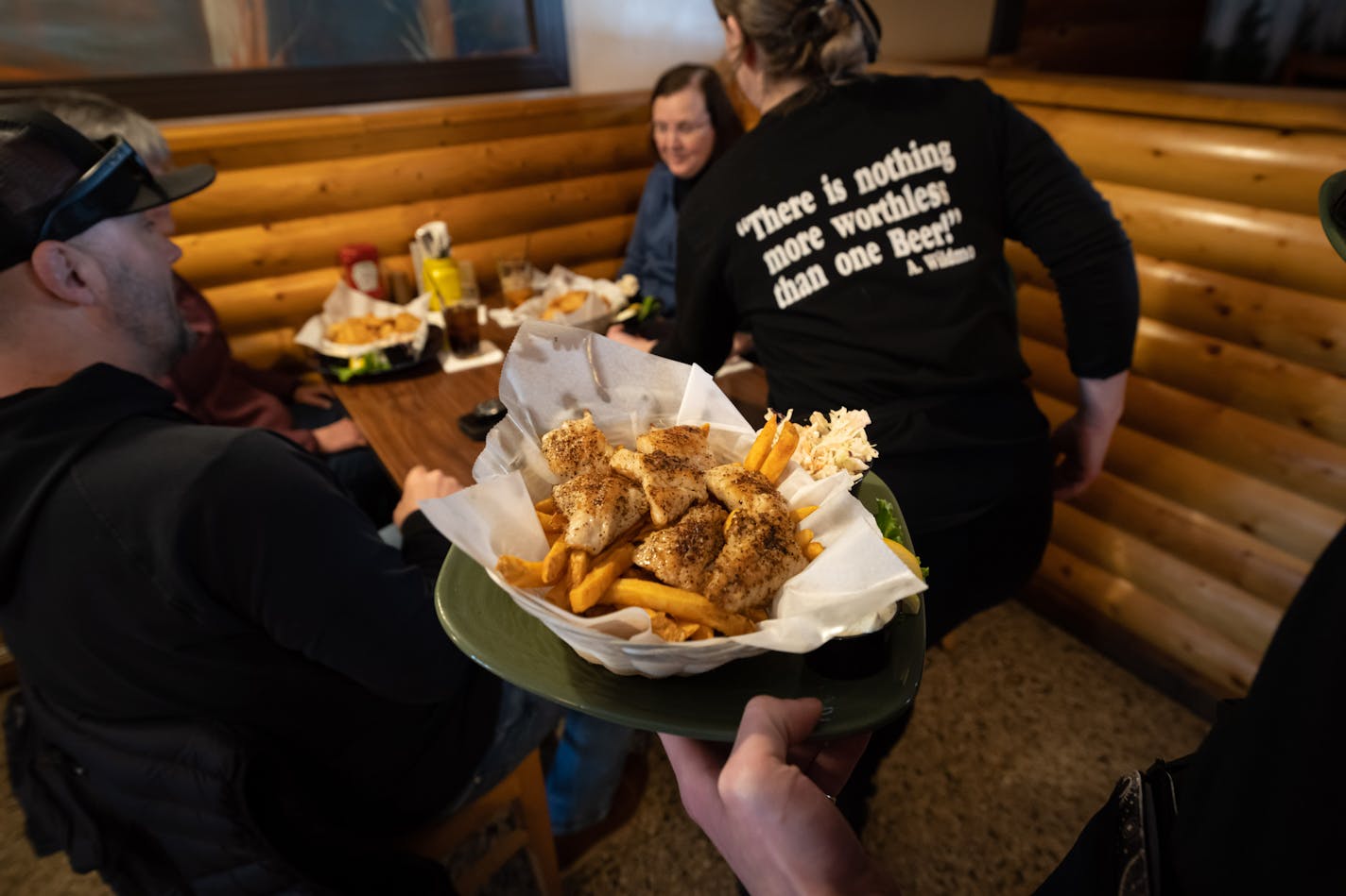 Server Harmony Lennon delivers food to a table at lunchtime at Tavern on Grand Thursday, March 9, 2023 St. Paul, Minn. Friday, March 10, 2023 St. Paul, Minn. This Grand Ave. institution claims to serve more walleye than any other restaurant in the world — 2,000 pounds a week. ] GLEN STUBBE • glen.stubbe@startribune.com