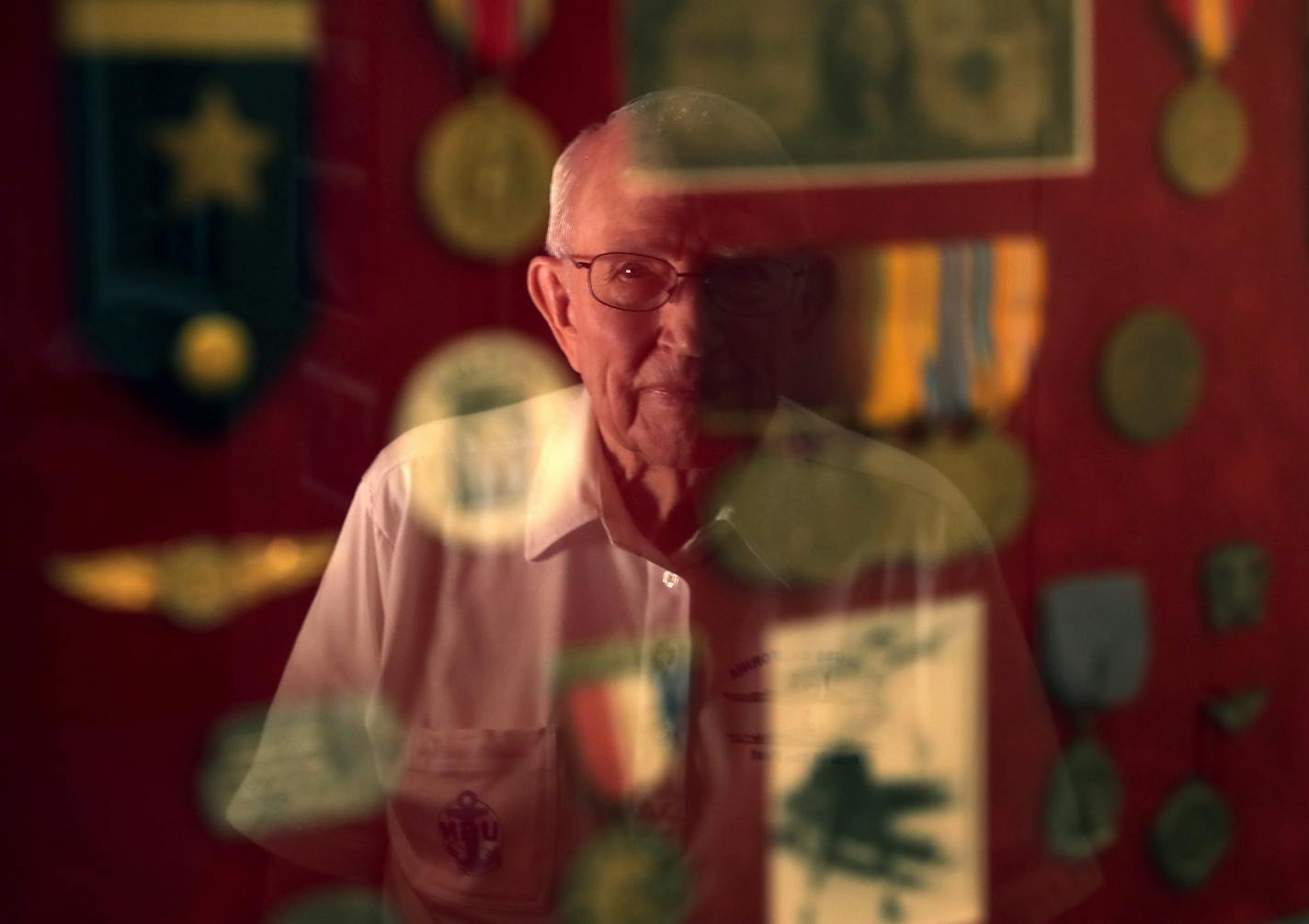 Vern Luettinger, 96, was a radio man on the USS California at Pearl Harbor on Dec. 7, 1941. Here, Vern is reflected in a framed collection of medals and keepsakes from that day 75 years ago when two torpedoes and a bomb struck the battleship, and he helped carry one of his wounded buddies to safety.