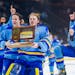 Goalie Nick Hansen carries the trophy as he and his St. Cloud Cathedral teammates celebrate their Class 1A boys hockey championship.