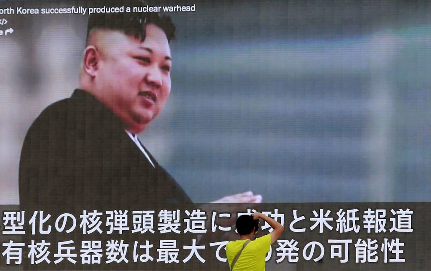 A man takes a photo of a TV news program in Tokyo, showing an image of North Korean leader Kim Jong Un Wednesday, Aug. 9, 2017. In an exchange of threats, U.S. President Donald Trump warned Pyongyang of "fire and fury like the world has never seen" and the North's military claimed Wednesday it was examining plans for attacking Guam.