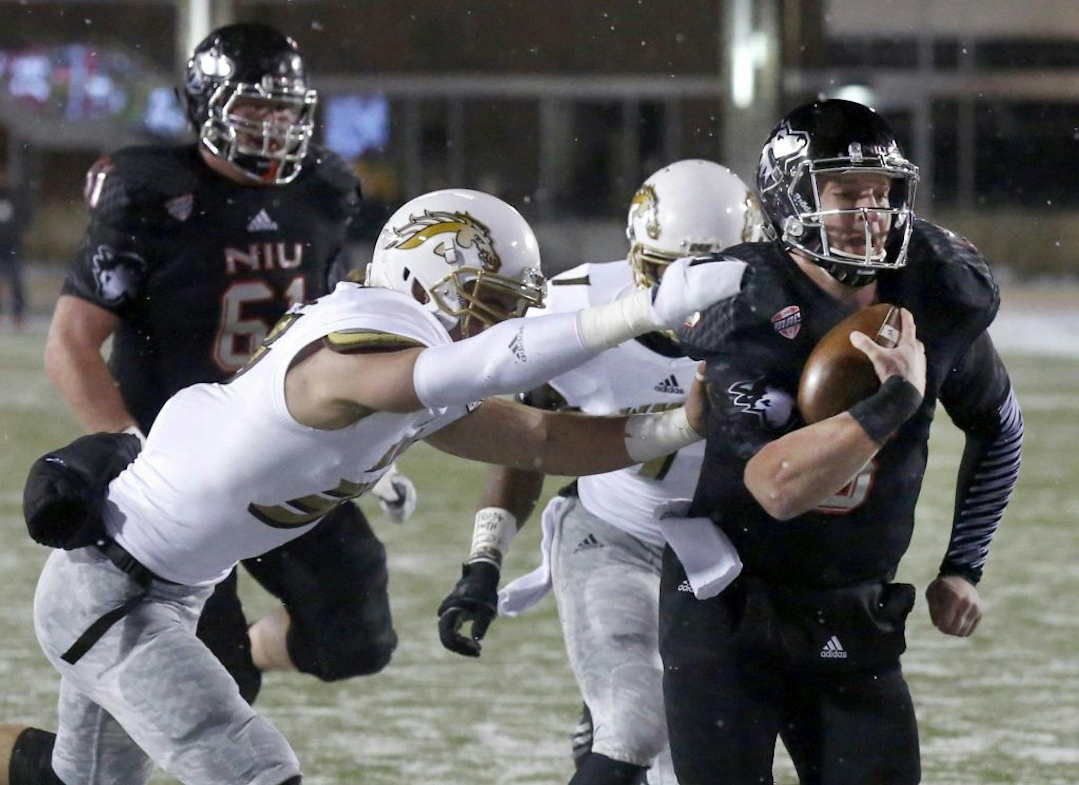 Northern Illinois quarterback Jordan Lynch carries the ball past two Western Michigan defenders during the first half of an NCAA football game Tuesday, Nov. 26, 2013, in DeKalb, Ill.