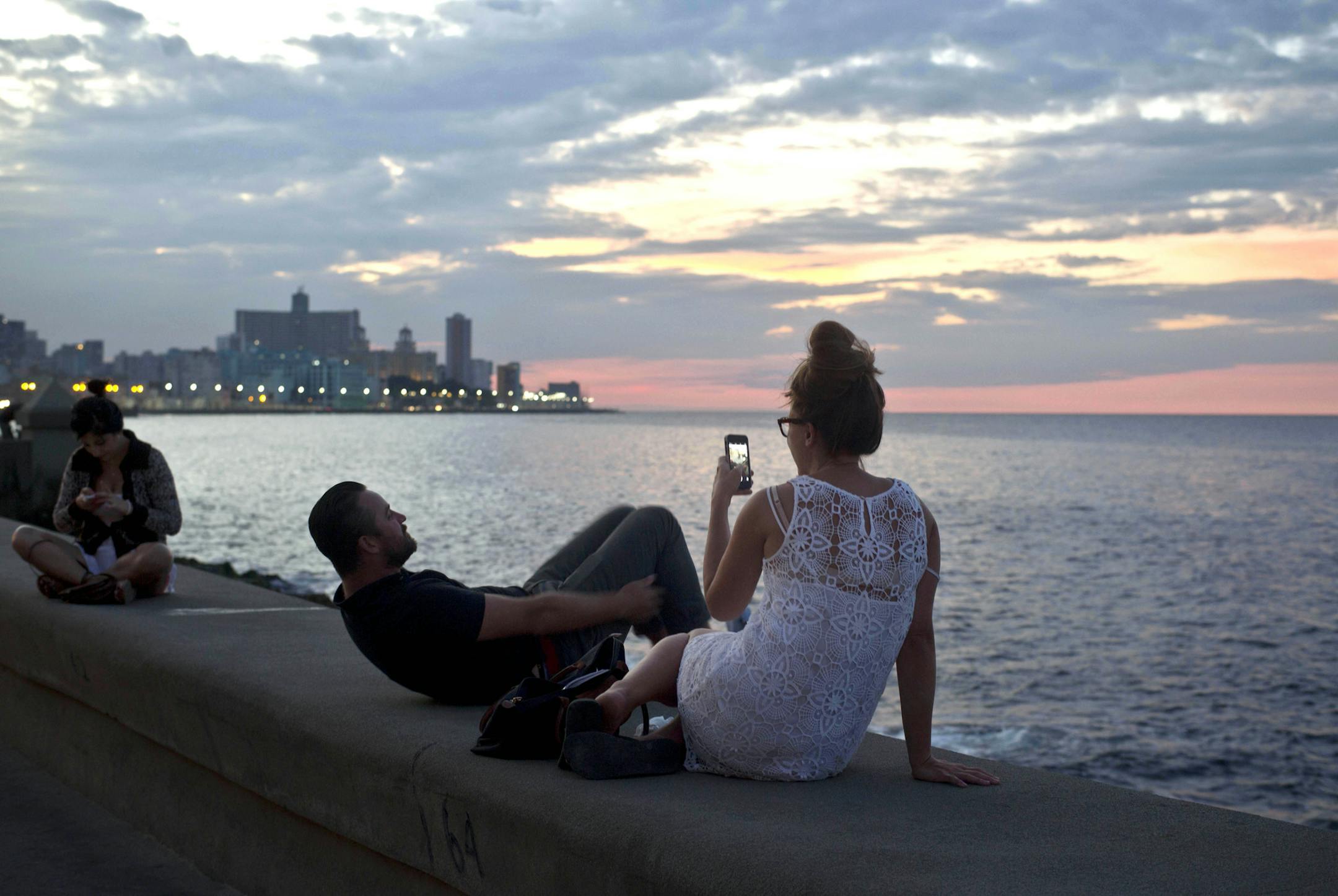 Tourists enjoy taking photos at the Malecon in Havana, Cuba, Friday, Dec. 19, 2014. After a half-century of Cold War acrimony, the United States and Cuba abruptly moved on Wednesday to restore diplomatic relations, a historic shift that could revitalize the flow of money and people across the narrow waters that separate the two nations. (AP Photo/Ramon Espinosa)