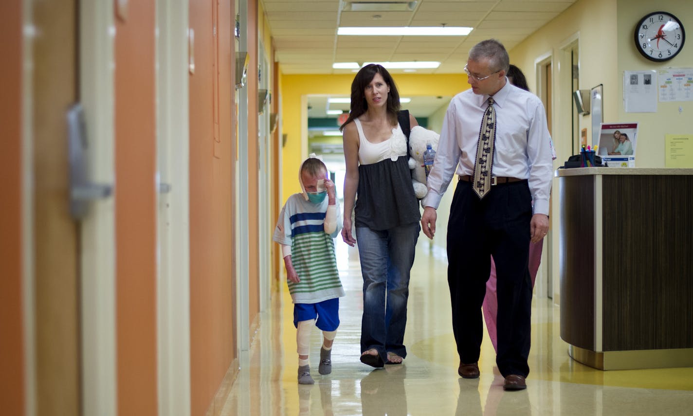 Dr. Jakub Tolar, right, director of the U of M's Stem Cell Institute, examined 7-year-old Charlie Knuth who has a rare and sometimes fatal genetic disease that causes the skin to slough off. Bone marrow transplants helped repair most of the boy's lesions, and he stands to benefit from new research spearheaded by Tolar and one of his graduate students who developed a molecular editing tool. The research illustrates the promise of an emerging field known as biomedical informatics. Charlie's mom Tr