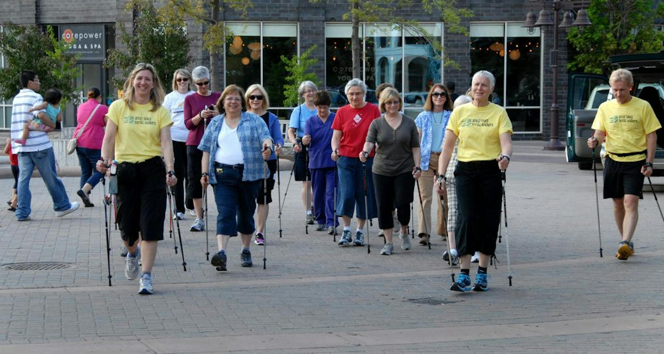 The Great Lakes Nordic Walkers Open House held at Centennial Lakes in Edina ended with a group walk. (Left to right) Walking in front, wearing matching yellow t-shirts, are Rhea Kontos, who runs a training and supply company called Nordic Walk This Way, and Linda Lemke, the Nordic Walking Queen and coordinator of the Hoigaard's Outdoor Women's program. Kontos and Lemke founded the Great Lakes Nordic Walkers.