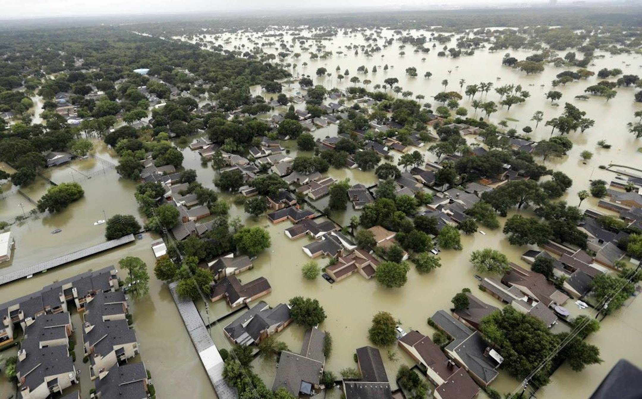 FILE - In this Aug. 29, 2017, file photo, water from Addicks Reservoir flows into Houston neighborhoods after Hurricane Harvey.