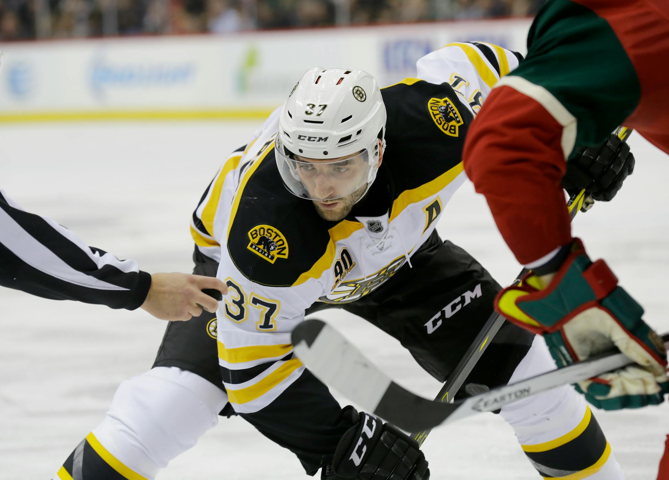 Boston Bruins center Patrice Bergeron (37) keeps his eyes on the puck in a face-off during the second period of an NHL hockey game against the Minnesota Wild in St. Paul, Minn., Tuesday, April 8, 2014. (AP Photo/Ann Heisenfelt)