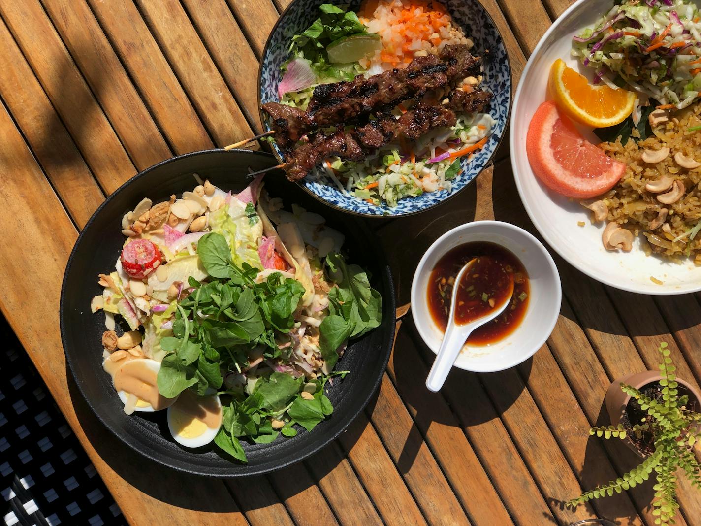 Several plates of colorful food topped with fresh fruit, herbs and sauces.