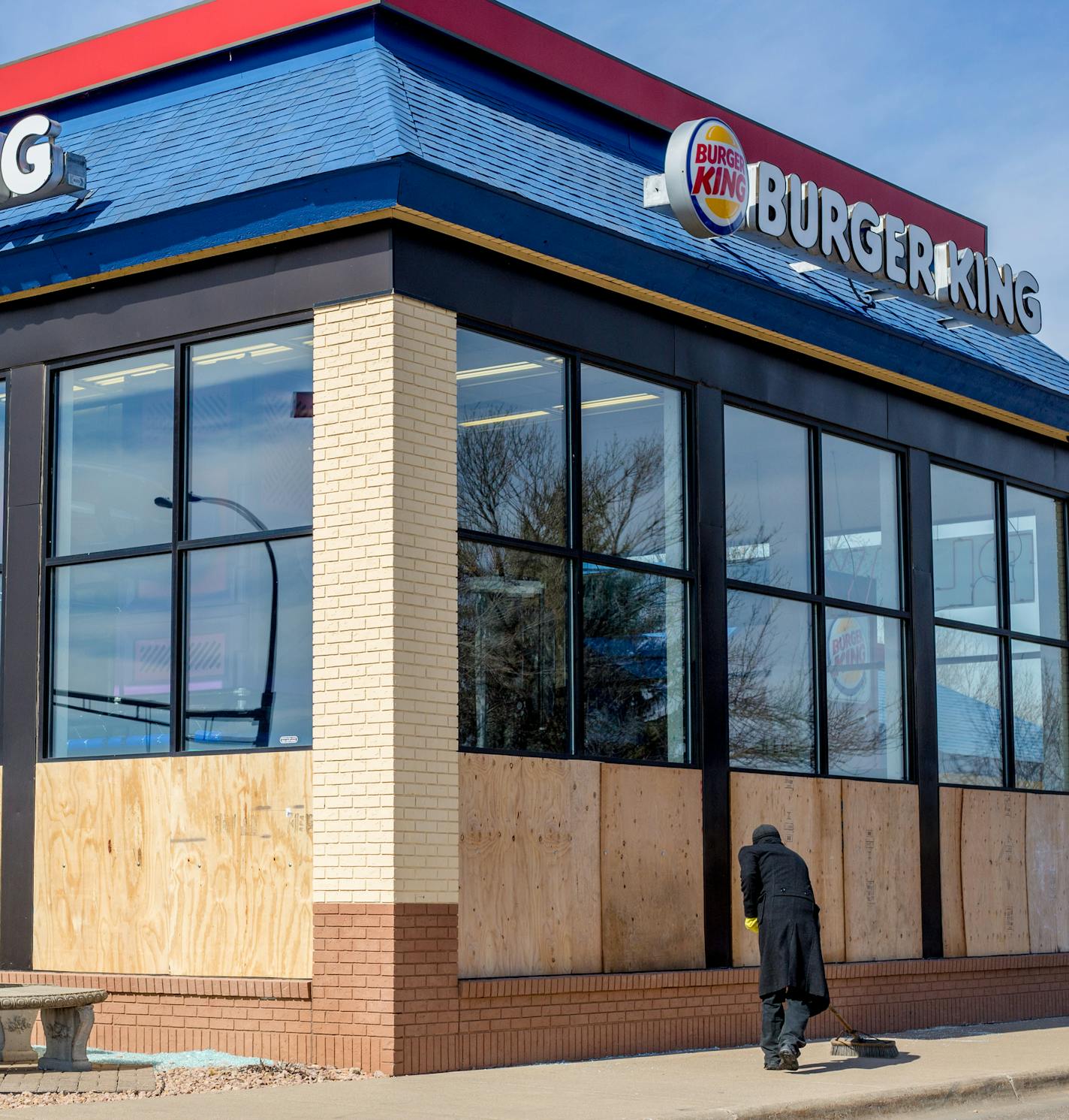 A man sweeps bits of broken glass that is now replaced by boards. ] Elizabeth Brumley special to the Star Tribune * A prank caller Friday night convinced the manager of a Coon Rapids Burger King to have employees smash out all the windows to keep the building from blowing up