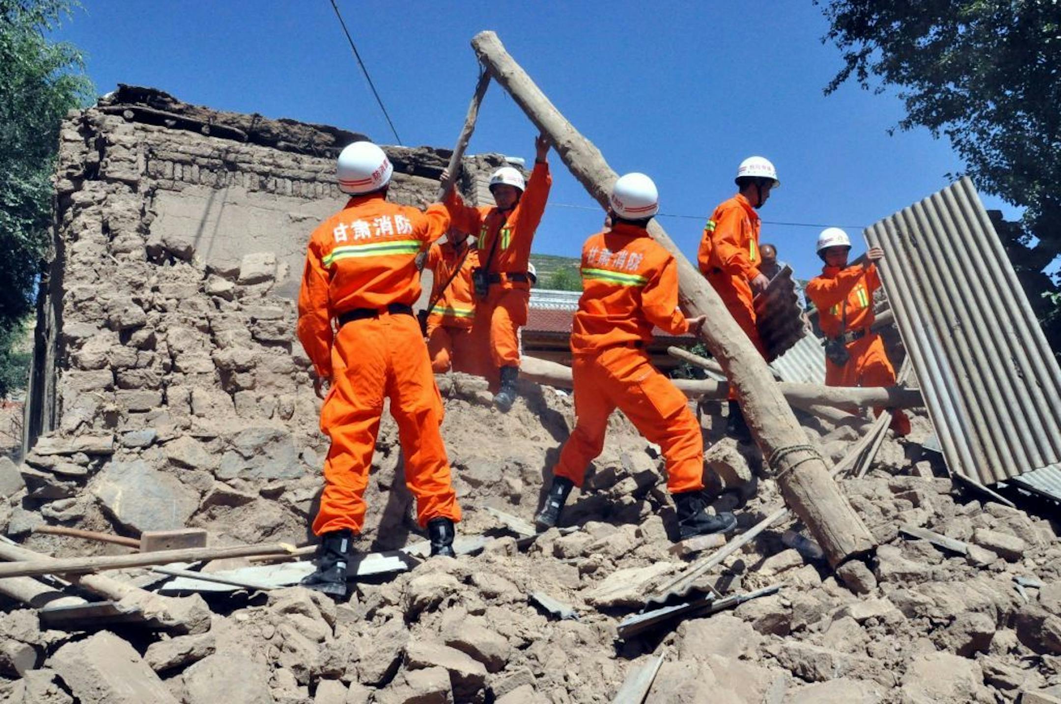 In this photo released by Xinhua News Agency, rescuers clear the debris of a damaged house in quake-hit Majiagou Village of Minxian County, northwest China's Gansu Province, Monday, July 22, 2013.