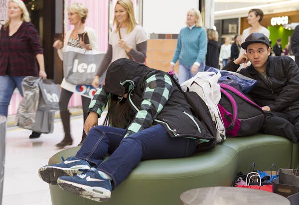 Sue Yuan, left, takes a nap as she and fellow University of Minnesota student Michael Zhang wait for their friends at the Mall of America in Bloomingt