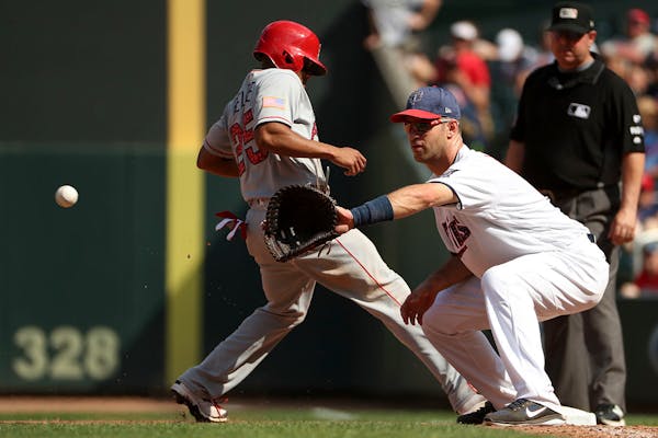 Los Angeles Angels left fielder Ben Revere (25) raced back to first as Twins first baseman Joe Mauer (7) checked him with a throw from the mound.