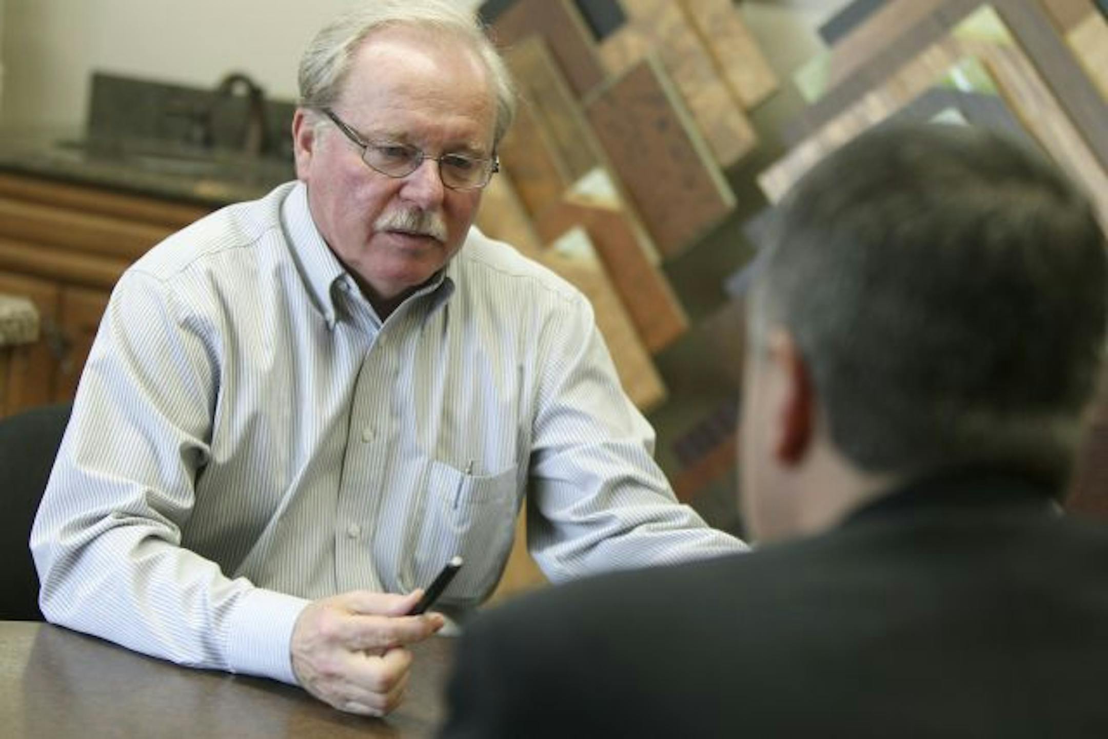 David Pahl of Bloomington Linoleum and Carpet listened to Roger Casper, back to camera, who left his U.S. Bank office to pay Pahl a visit and discuss a loan.